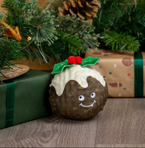 Christmas pudding-shaped toy with a face, surrounded by Christmas decorations and presents.