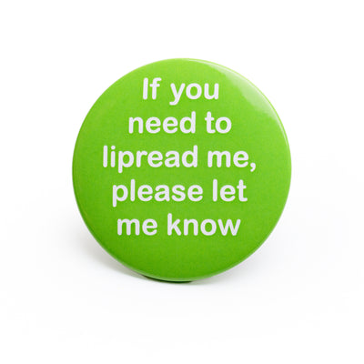 Large green pin badge with white lettered message 'If you need to lipread me, please let me know' on white background