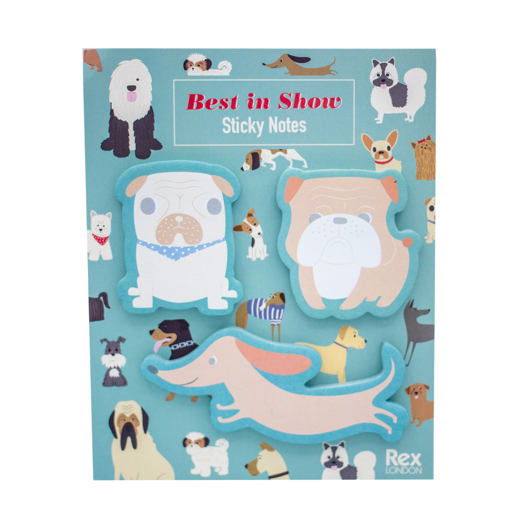 Front view of outer packaging of Best in Show Sticky Notes. The packaging is light blue with illustrations of different breeds of dog printed on the background. The 3 dog-shaped sticky note pads are visible and stuck to the front packaging. Each sticky pad is in the shape of a different dog breed, including a Pug, Bulldog and Dachshund.
