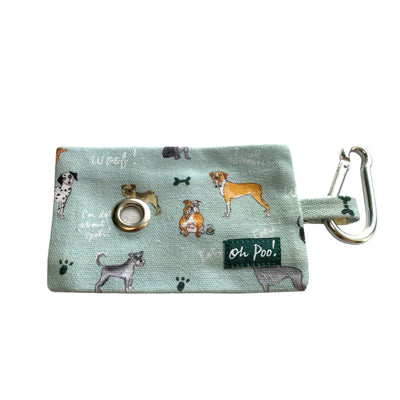 Images shows a cotton fabric holder for carrying poop bags (poop bags not included). It comes with a clip for attachment to a belt or bag and a handy metal porthole for easy access to a bag which can be pulled through.The holder has a lovely light blue background with a colourful, illustrated dog pattern. Featuring lots of different canine drawings