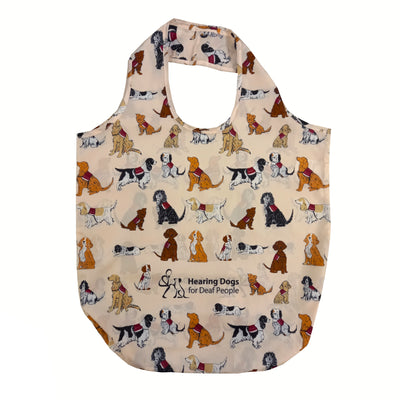 Small folded up bag in pouch on the left and unfolded shopper bag on the right. The bag features sketch illustrations of dogs of different sizes, colours and breeds all wearing the official Hearing Dogs jacket.