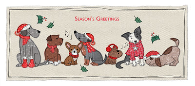 A rectangular Christmas-themed rug or mat featuring illustrated dogs wearing red Santa hats and scarves, with holly leaves and the words 'Season's Greetings' on a cream background.