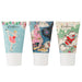 Front on photo of the 3 hand creams in a row, as if they were standing upright on their white lids. The packaging of the far-left hand cream is a pale blue with white stars, with an ice skater girl holding her leg up behind her. The middle hand cream's packaging is dark blue with a big pink Christmas Tree and other festive illustrations. The packaging of the far-right hand cream is cream with the outline of green buildings, with an illustration of Santa in a snow cloud.