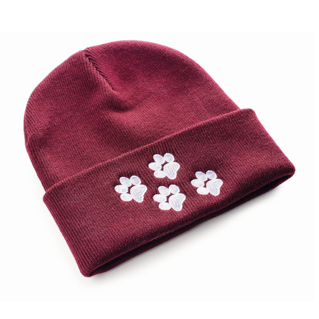 A burgundy beanie hat with four paw prints close together on the turned up edge.