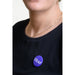 Person wearing blue pin badge with white wording DEAF