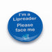 Blue pin badge featuring white lettered message 'I'm a lipreader, please face me' on a white background