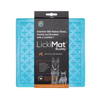 Face-on view of the Lickimat Buddy in turquoise in its packaging. The turquoise mat has a black cardboard sleeve down the middle with a black and white photograph of a German Shepherd and a French Bulldog. There is subtext which says:  'Entertain and Reduce Stress, Anxiety and Boredom with a Lickimat! Great for all sizes and breeds'. 