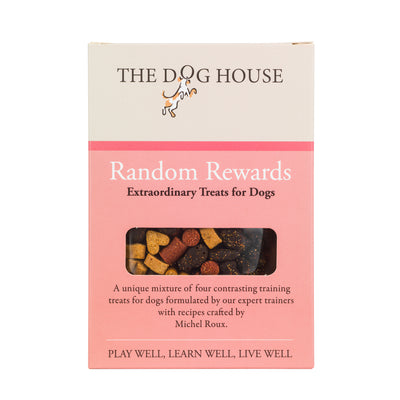 Square, pink and cream box that has the words 'The Dog House Random Rewards' on it with a small pile of treats visible through a transparent window in the box. The treats are different colours and shapes such as hearts, bones and tubes.