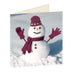 Square Christmas card, stood up at an angle, featuring a photo of a happy snowman with his gloved hands in the air. The snowman is wearing a hat with pawprints on, a scarf and gloves all in the Hearing Dogs burgundy.